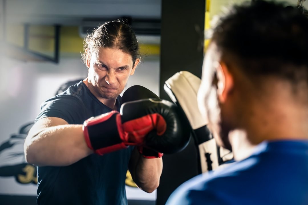 caucasian fitness instructor teach sportsman doing boxing or muay thai in gym .jpg